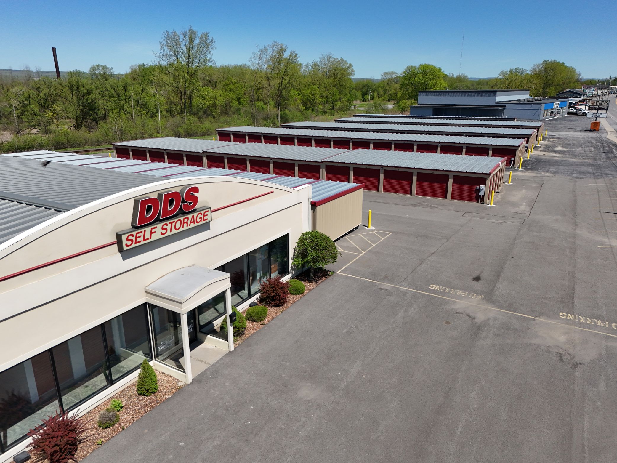 Aerial view of A-Verdi Self Storage office building with red storage units, paved driveways, and wooded surroundings.